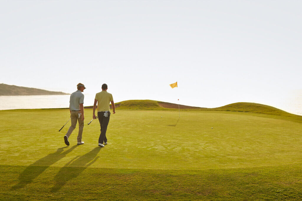 Two men walking and talking at a golf course